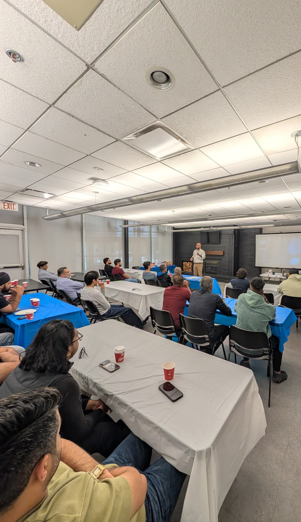An MWS trainer presents to a room of drivers seated at tables during an in-person training session.